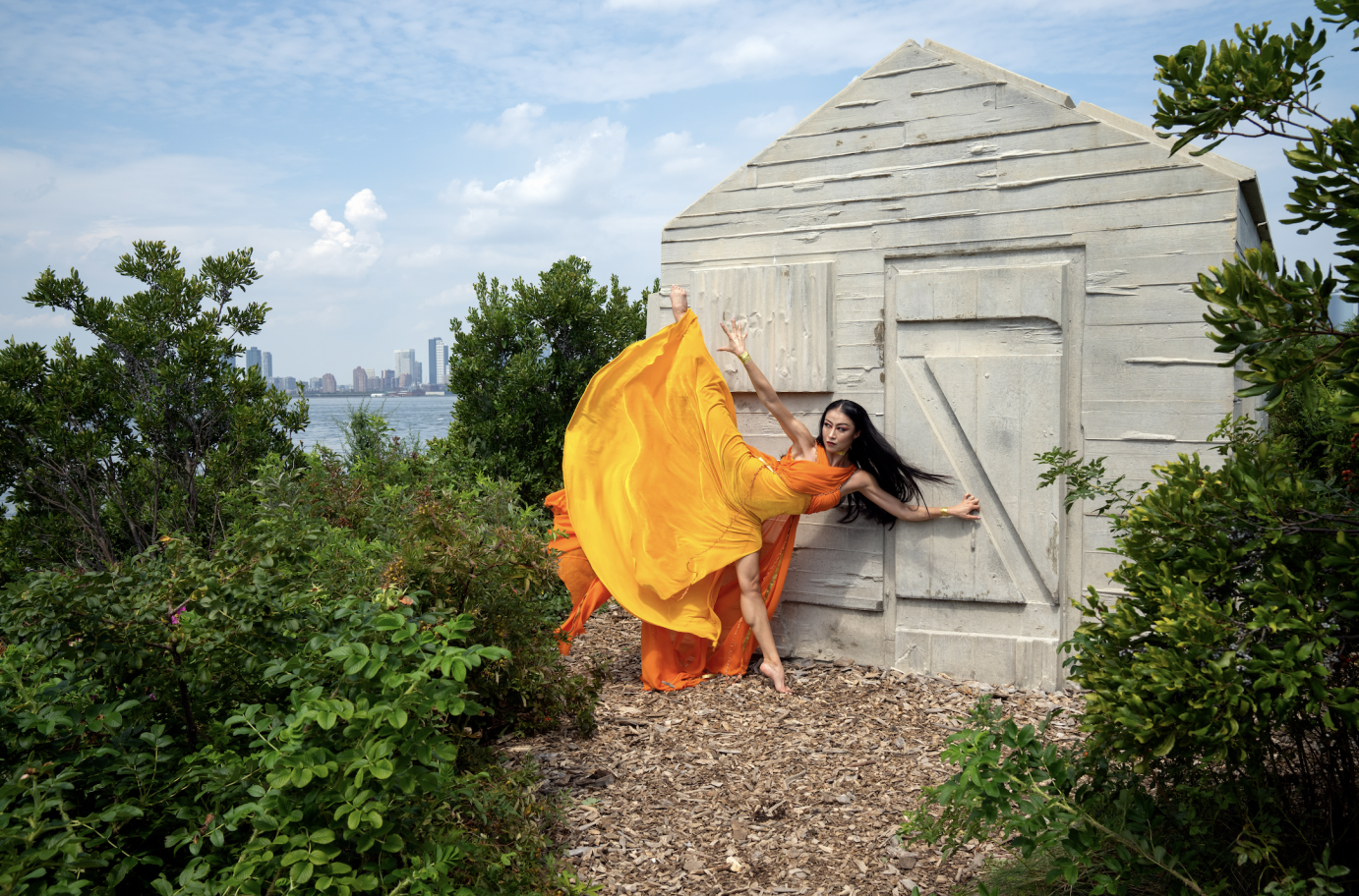 PeiJu Chien-Pott extends a leg high to the side. She leans against the door to a cabin.